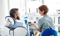 Smiling dental assistant and patient looking at X-ray