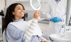 Woman smiling at reflection in handheld mirror