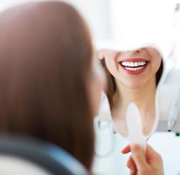 Woman looking at her smile after advanced dental services and technology