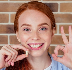 Woman holding up extracted wisdom tooth