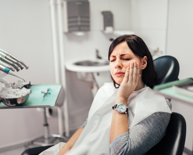 Woman holding cheek before emergency dentistry