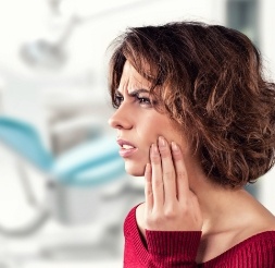 Woman in need of emergency dentistry holding cheek in pain