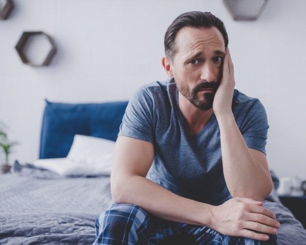 Man in need of emergency dentistry holding jaw in pain