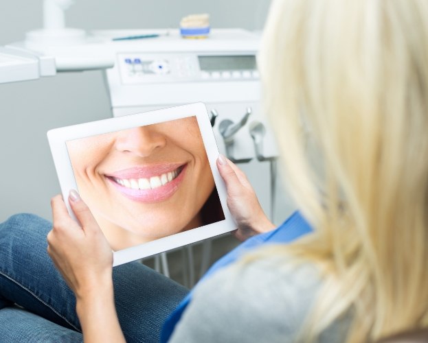 Woman looking at virtual smile design on tablet computer