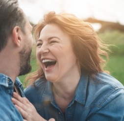 Woman laughing outdoors after dental restoration