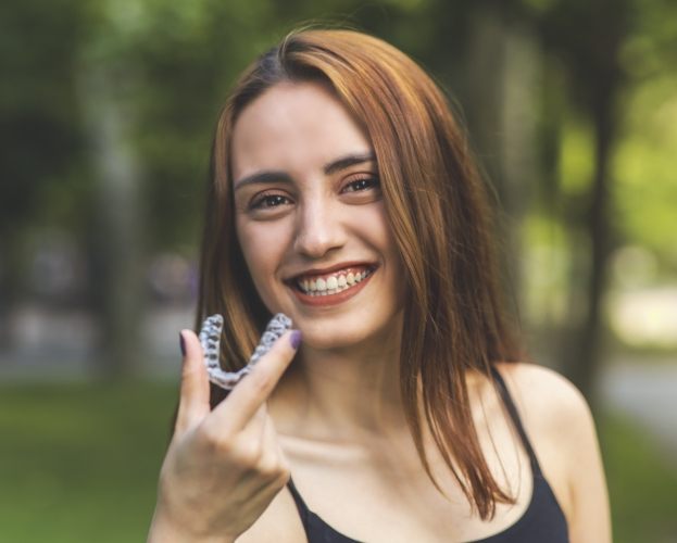 Woman holding her Invisalign clear aligner