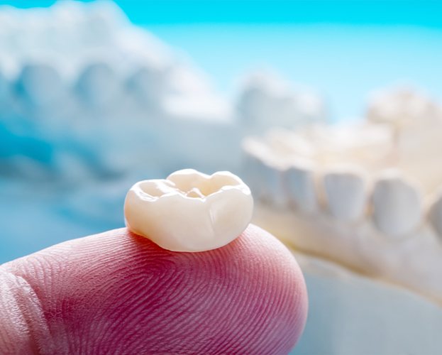 Biocompatible zirconia dental crown on fingertip