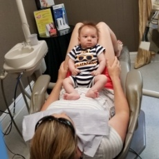 Mother holding infant during first dental checkup