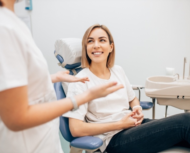 Woman in dental chair smiling at dentist