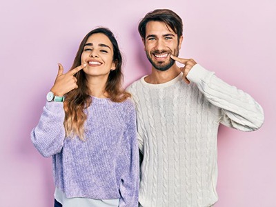 Young couple pointing at their teeth