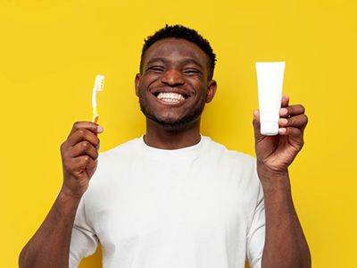 Smiling man holding toothbrush and toothpaste