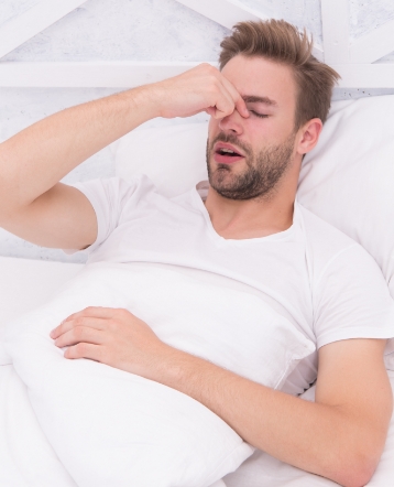 Man in need of emergency dentistry holding cheek in pain